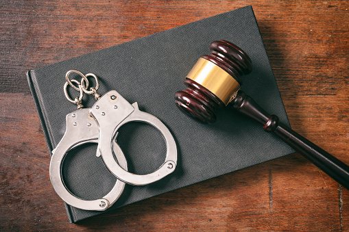 Silver handcuffs, a wooden gavel, and a black legal book for a criminal case in Glen Burnie, MD